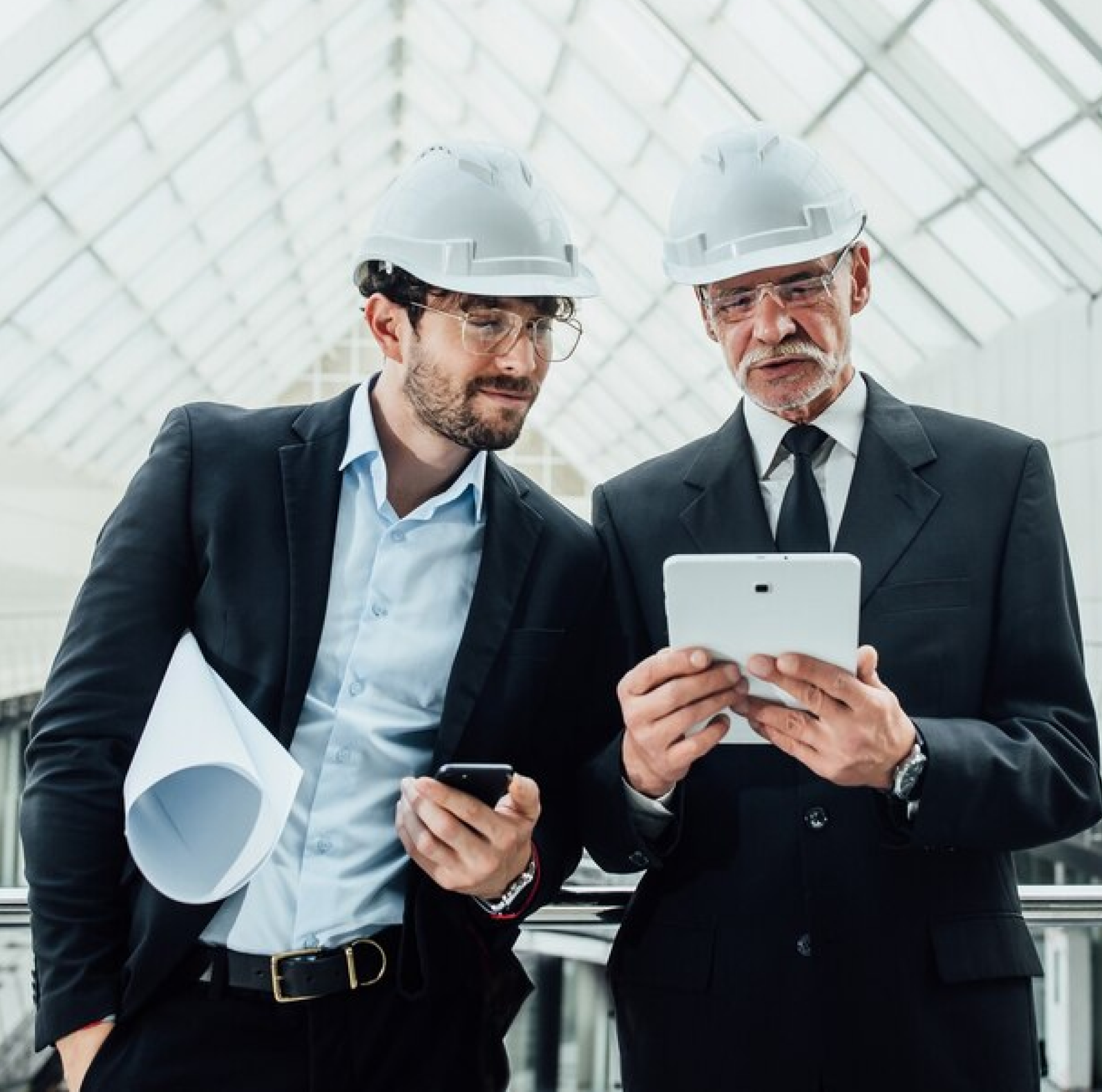 Two professionals in hard hats reviewing tablet